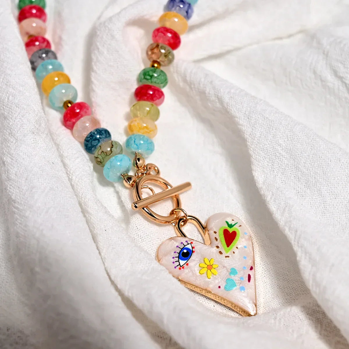 Collar de cuentas de piedras preciosas multicolor con colgante de corazón pintado.