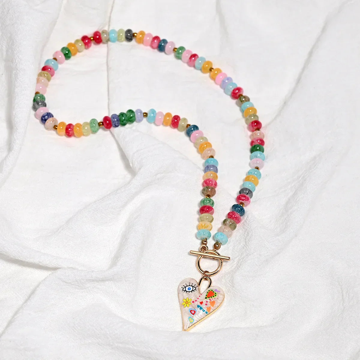 Collar de cuentas de piedras preciosas multicolor con colgante de corazón pintado.