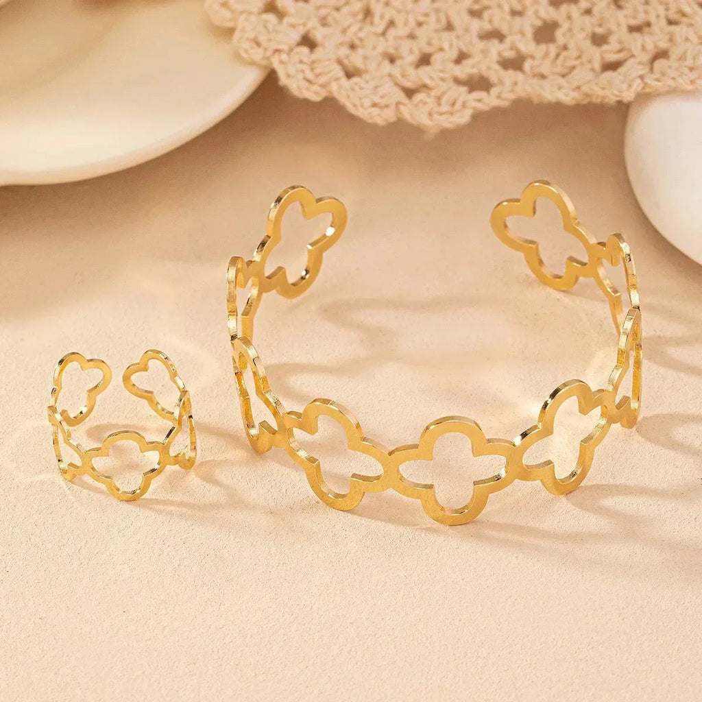 Conjunto de pulsera y anillo ajustables con delicado diseño de trébol de cuatro hojas abierto.