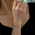 Conjunto de pulsera y anillo ajustables con delicado diseño de trébol de cuatro hojas abierto.