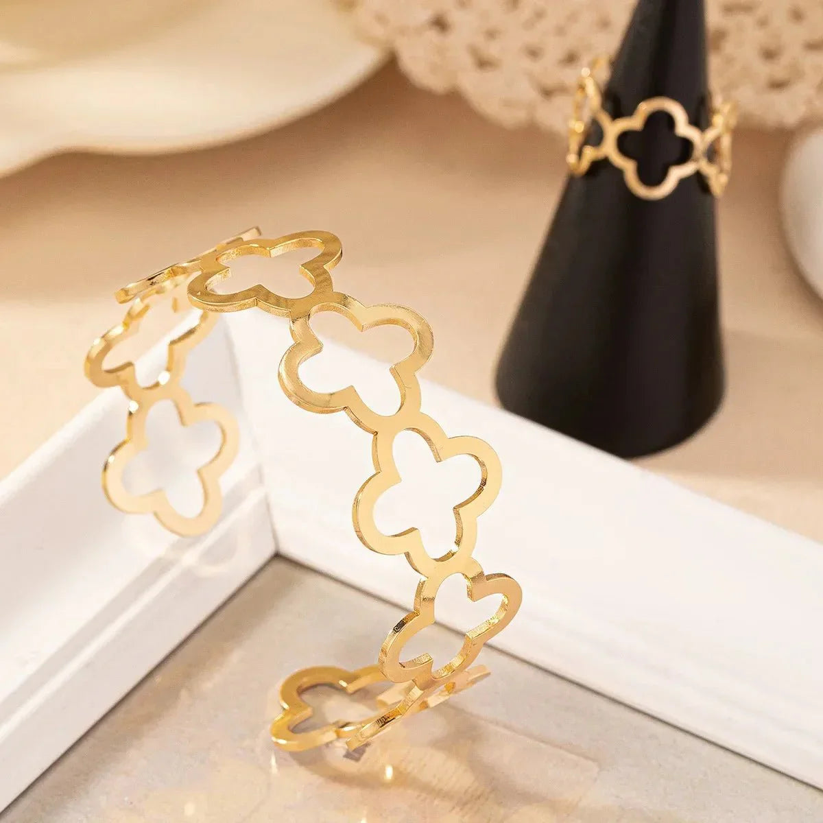 Conjunto de pulsera y anillo ajustables con delicado diseño de trébol de cuatro hojas abierto.